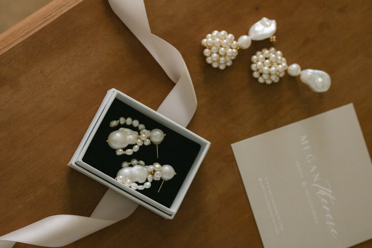 Handcrafted pearl and floral bridal earrings  by Megan Therese, an Irish wedding jewellery designer, displayed on a table as part of the Try Before You Buy Bridal jewellery service. 